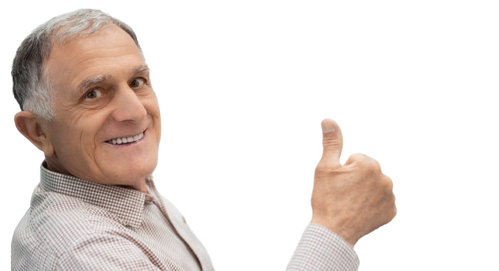 Senior man sitting in a dental chair giving a thumbs up.