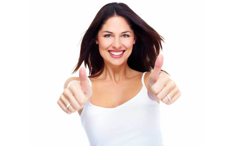 Woman in white tank top smiling and giving a thumbs up